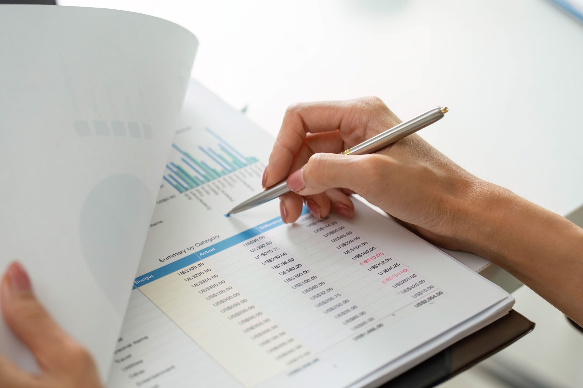 Report Review and Notes. Close-up of a professional woman analyzing financial data with a pen.
